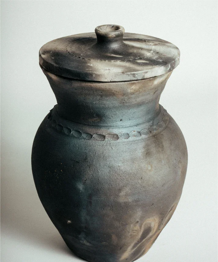 Vaso de cerâmica artesanal com tampa, detalhes em relevo e acabamento rústico, preservando técnicas ancestrais.